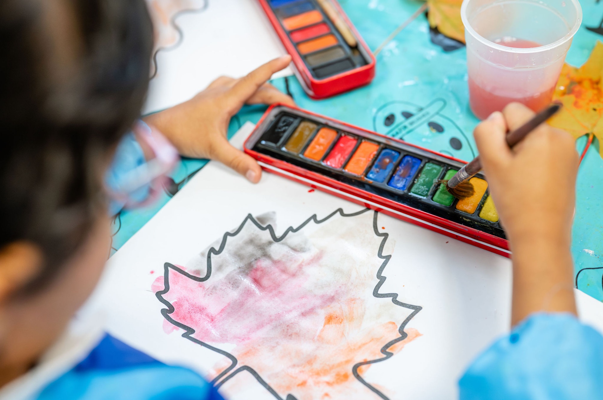 A child paints a picture of a leaf