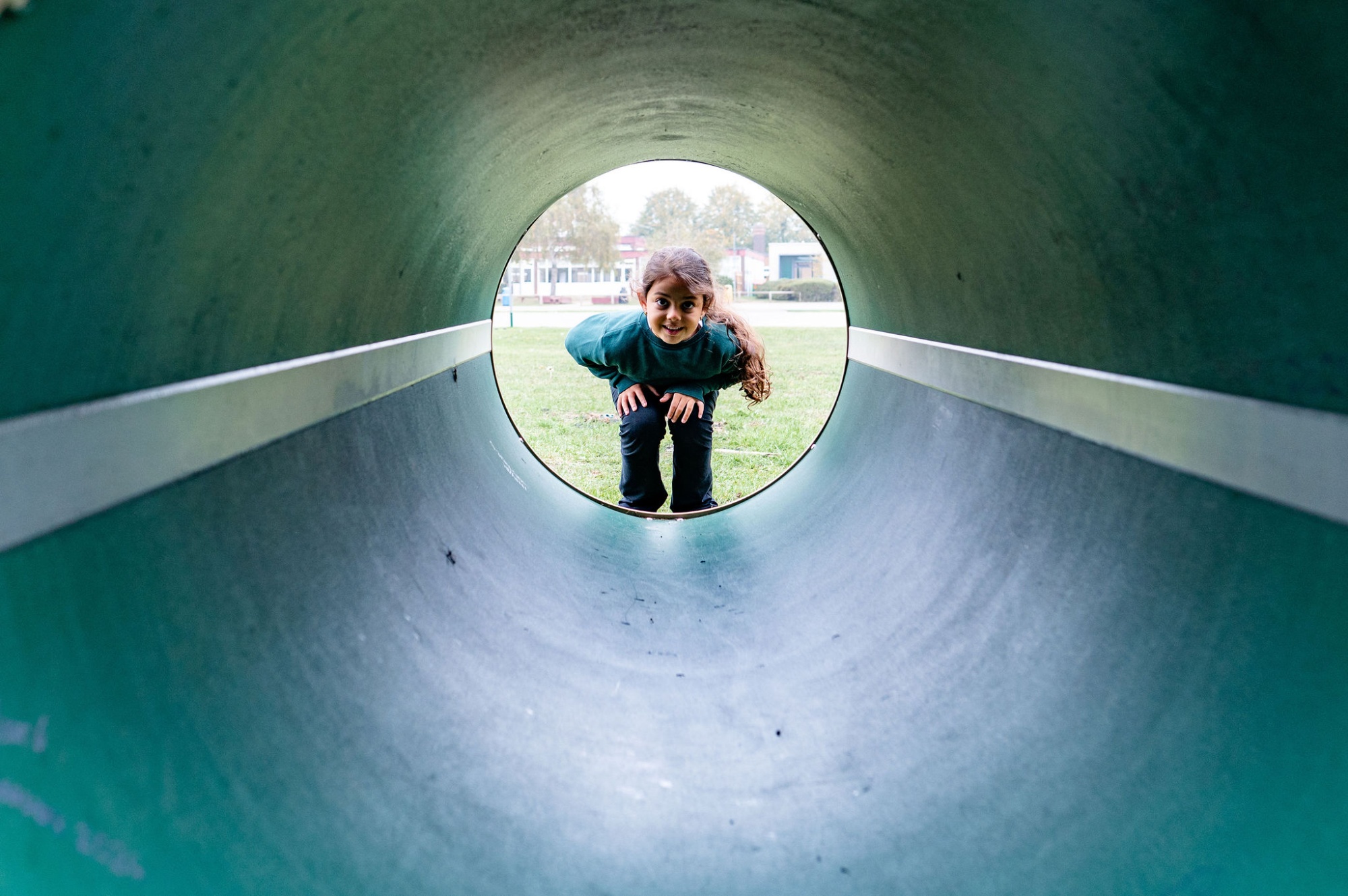 A child looks through a tunnel in the playground